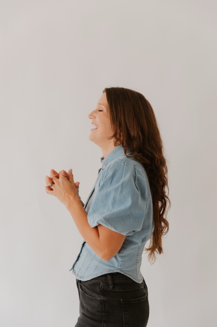 Rachel laughing with her hands clasped